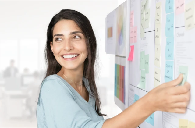 A person arranges notes on a project board to support workflow planning and process optimisation in an office.